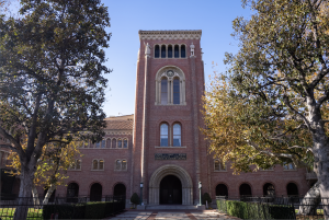 Bovard Auditorium partially covered by trees and illuminated by the sunlight